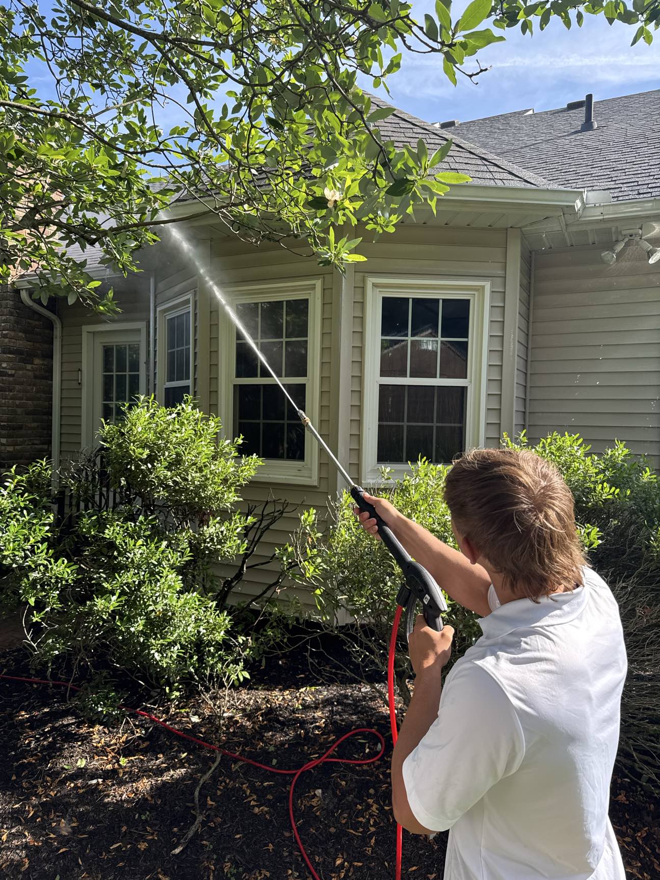 Ducky's team member soft washing the exterior and windows of a home