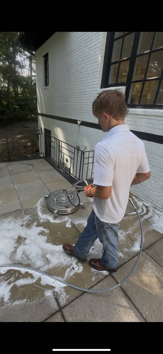 Ducky's team member using a surface cleaner on a stone patio